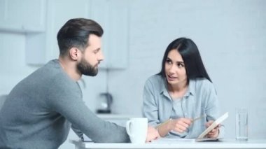 Kadın, üzgün adamı hesap makinesinin yanına götürüyor. 