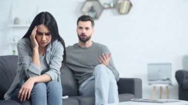 Mutsuz erkek arkadaşın yanında oturan üzgün kadının seçici odağı 