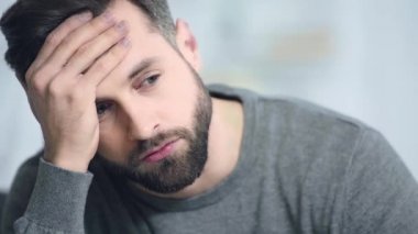 endişeli ve sakallı bir adam yüzüne dokunuyor 