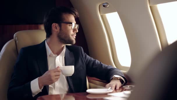 Επιχειρηματίας Κρατώντας Καφέ Και Κοιτάζοντας Illuminator Ενώ Ταξιδεύετε Αεροπλάνο — Αρχείο Βίντεο