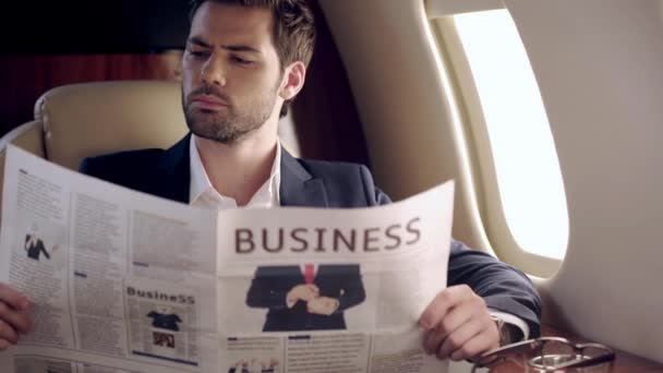 Σοβαρός Προσεκτικός Επιχειρηματίας Που Διαβάζει Εφημερίδα Ενώ Ταξιδεύει Αεροπλάνο — Αρχείο Βίντεο