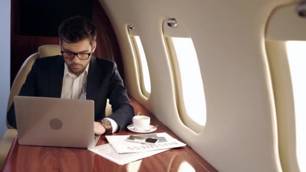 Seriózní Podnikatel Pomocí Notebooku Blízkosti Novin Šálek Kávy Letadle — Stock video