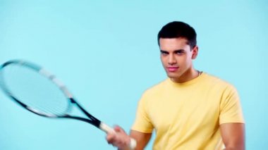 Tenis raketi tutan mutlu adam mavi üzerine izole edilmiş.
