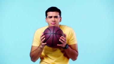 Heyecanlı spor fanatiği basketbolun galibi mavi üzerine izole edilmiş jest gösteriyor