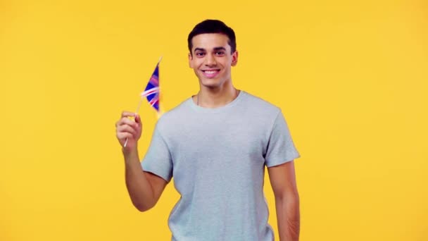 イギリスの小さな旗を持つ幸せな男は黄色に隔離されたこんにちはを示しています — ストック動画