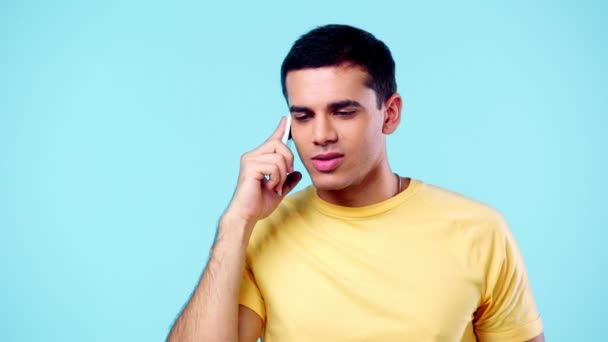 Pohledný Mladý Muž Usmívá Zatímco Mluví Smartphone Izolované Modré — Stock video