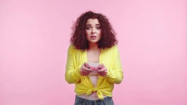 KYIV, UKRAINE - 12 Kasım 2019: Pembe üzerinde izole edilmiş joystick 'i olan üzgün kız