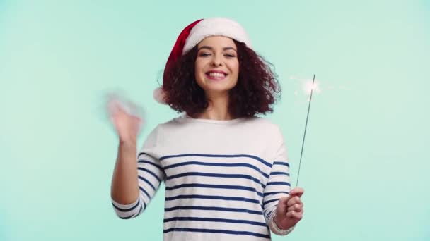 Alegre Chica Santa Hat Celebración Sparkler Agitando Mano Aislado Turquesa — Vídeos de Stock