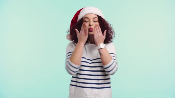 Happy Curly Girl Santa Hat Blowing Air Kiss Isolated Turquoise — Stock Video