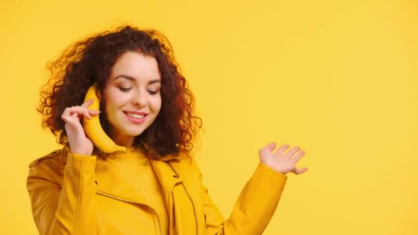 黄色に隔離されたバナナとの電話会話を真似て陽気な女の子 — ストック動画