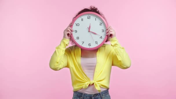 Menina Alegre Gesticulando Obscurecendo Fae Com Relógio Redondo Isolado Rosa — Vídeo de Stock