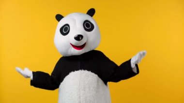 Panda kostümlü bir insan başparmağını sarı renkte gösteriyor. 