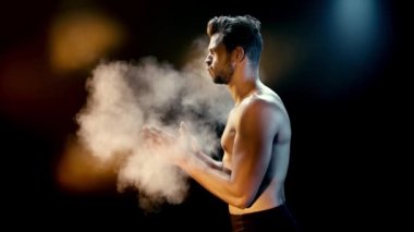 Siyah talk pudrasıyla el çırpan sporcunun yan görünüşü 