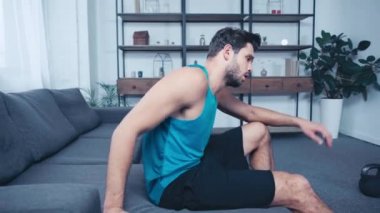 Yorgun sporcu evdeki kanepede dinleniyor.