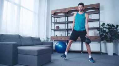 Genç sporcu evde ağırlıkla egzersiz yapıyor.