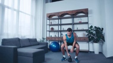 Genç sporcu evde ağırlıkla egzersiz yapıyor.