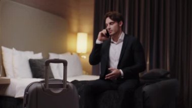 Bavulun yanında akıllı telefondan konuşan genç işadamlarının seçici odak noktası 