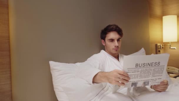 Joven Hombre Concentrado Leyendo Periódico Negocios Mientras Descansa Cama — Vídeos de Stock