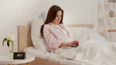 Yatakta dizüstü bilgisayar kullanan çekici bir serbest yazar. 