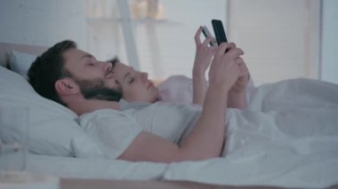 Yatakta akıllı telefon kullanan çiftlerin seçici odak noktası 