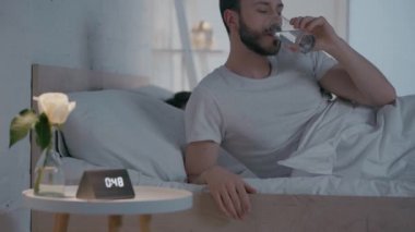 Geceleri uyuyan kadının yanında su içen bir erkeğin seçici odağı.