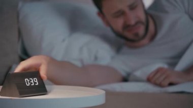 Geceleri uykusuzluk çekerken saate bakan adamın seçici odağı