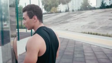 Sporcu gülümsüyor ve oyun parkının yakınındaki kameraya bakıyor.