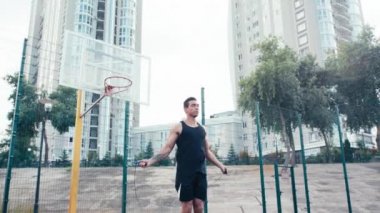 Sporcunun basketbol sahasının yanında ip atlarken alçak açılı görüntüsü. 