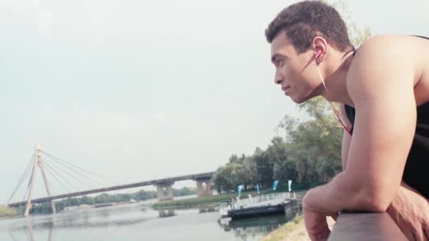 Sportler Mit Kopfhörern Lehnt Zaun Lächelt Und Blickt Auf Den — Stockvideo