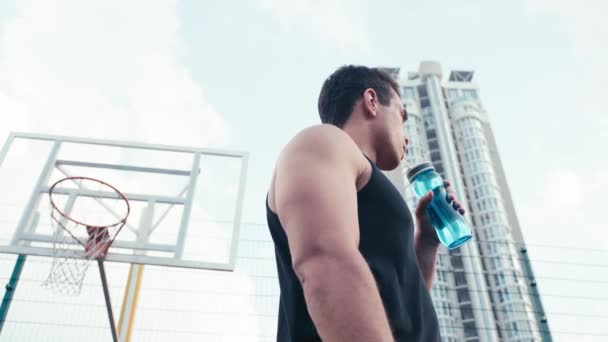 道路上の空に対して水を飲むスポーツマンの低角度ビュー — ストック動画