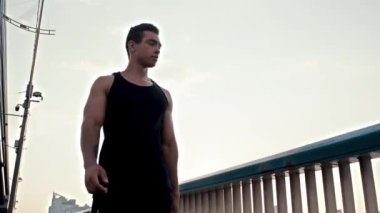 Köprüde gökyüzüne karşı yürüyen sporcunun alçak açılı görüntüsü