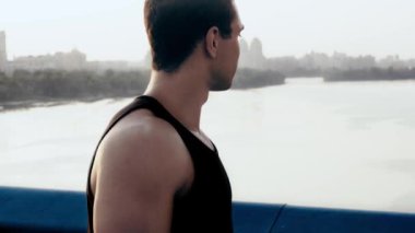 Sporcu gülümsüyor ve köprüdeki kameraya bakıyor.