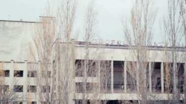 CHERNOBYL, UKRAINE - 6 Kasım 2019: Kültür sarayı ve ağaçların yanındaki enerjik harflerle terk edilmiş bina 