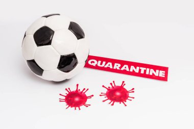 Kağıdın yanındaki futbol topunda karantina harfleri ve beyaz üzerine virüs çizilmiş.