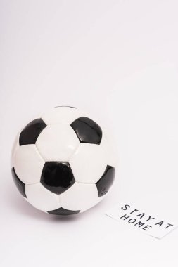Futbol topu kağıdın yanında, evde kalıp beyaz harflerle yazılıyor. 