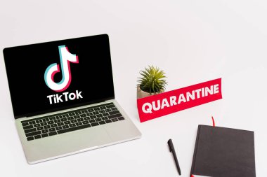 KYIV, UKRAINE - 8 Nisan 2020: Tik tok web sitesi beyaz karantina harfli yeşil bitki, kalem, not defteri ve kağıdın yanında ekranda 