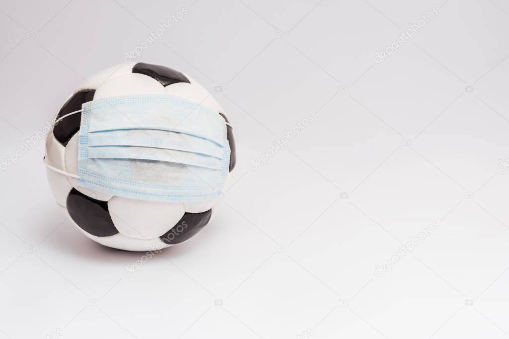 soccer ball in medical mask on white with copy space