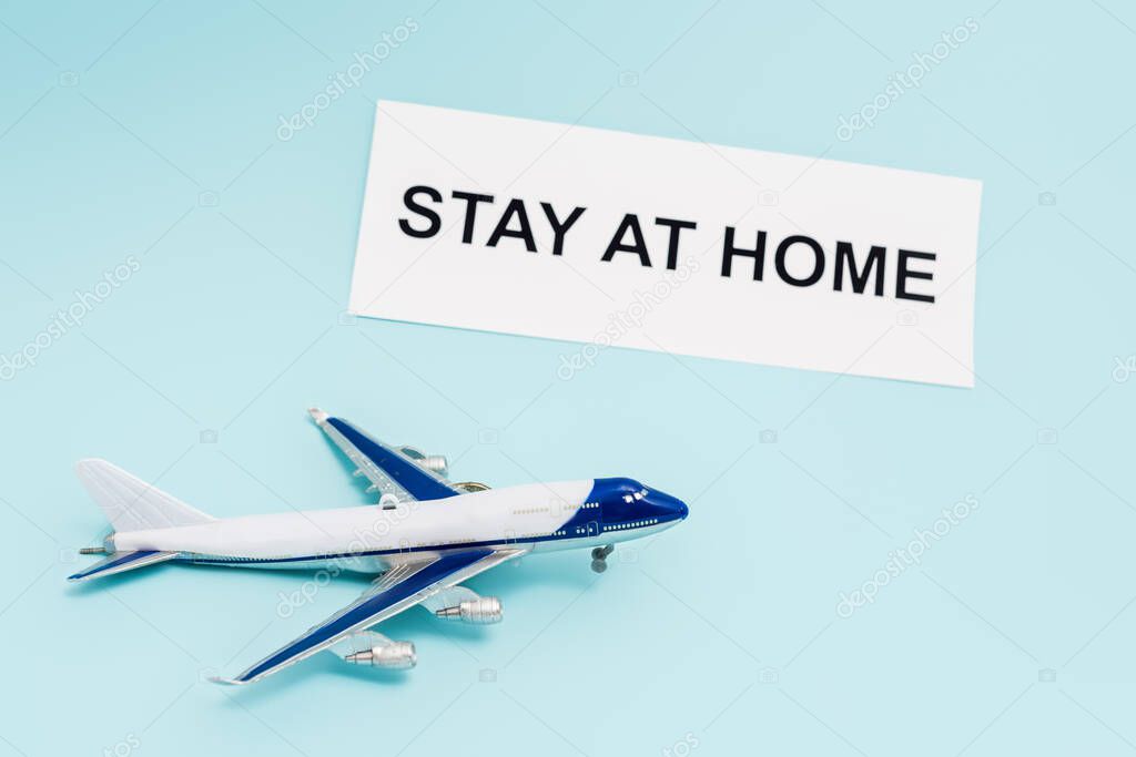toy plane near paper with stay at home lettering on blue 