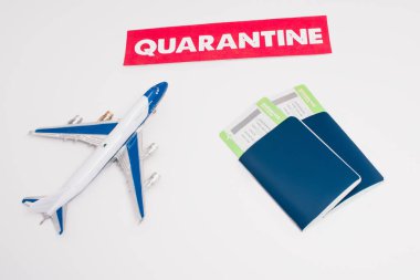 High angle view of toy near card with quarantine lettering and passports with air tickets on white background clipart