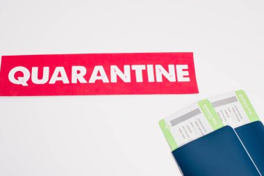 Karantina harflerinin olduğu yüksek açılı bir kart ve beyaz üzerine uçak bileti olan pasaportlar.