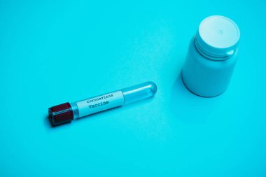 Mavi üzerinde Coronavirus aşısı ve kabı olan test tüpünün yüksek açılı görüntüsü