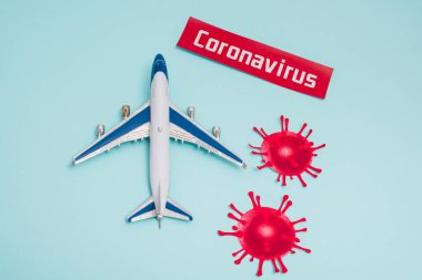 Kartın yanında Coronavirus harfleri ve dekoratif koronavirüs molekülleri olan oyuncağın en üst görünümü mavi