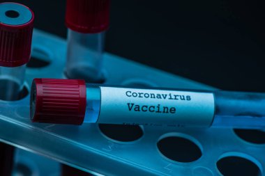 Koyu arkaplanda koronavirüs aşısı olan test tüpü rafı