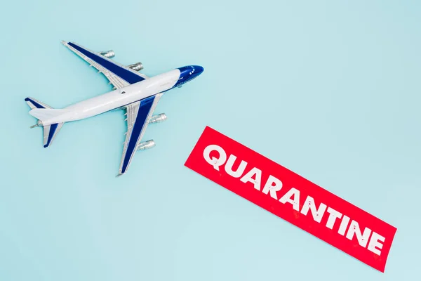 Top view of toy plane near paper with quarantine lettering isolated on blue — Stock Photo