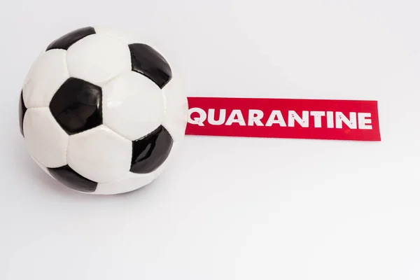 Soccer ball near paper with quarantine lettering on white — Stock Photo