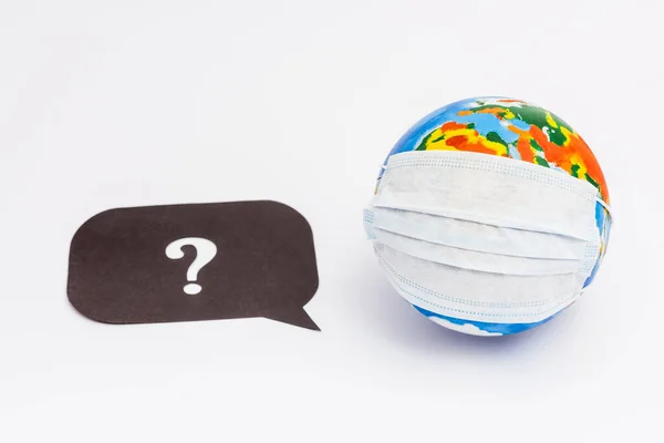 Globe in medical mask near speech bubble with question mark on white — Stock Photo