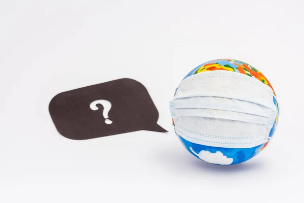 Globe in protective medical mask near speech bubble with question mark on white — Stock Photo