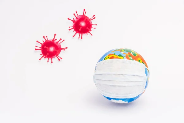 Globo in maschera medica protettiva vicino virus disegnato rosso su bianco — Foto stock