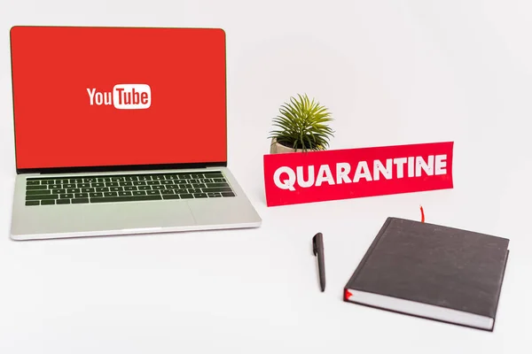 KIEW, UKRAINE - 8. April 2020: Laptop mit Youtube-Website auf dem Bildschirm in Werksnähe, Stift, Notizbuch und Papier mit Quarantäne-Schriftzug auf weiß — Stockfoto