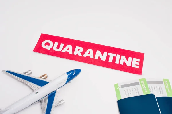 High angle view of toy near card with quarantine lettering and passports with air tickets on white — Stock Photo